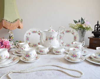 May include: A vintage floral tea set with a teapot, creamer, sugar bowl, and four teacups and saucers. The set features a delicate floral pattern with pink, blue, and white flowers on a white background.