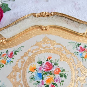 May include: A white and gold decorative tray with a floral design. The tray has a raised rim with gold accents and a floral pattern painted on the surface.