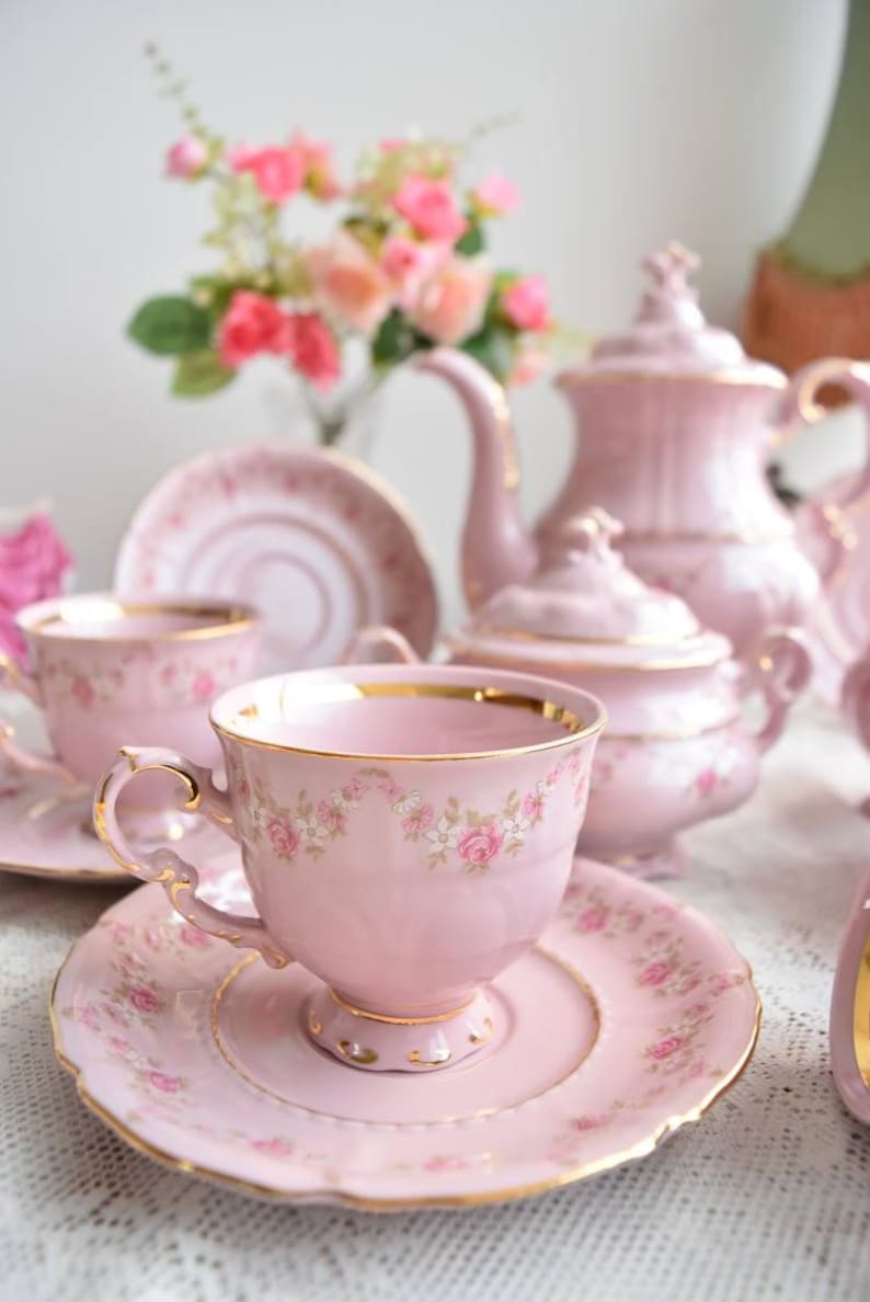 Puede incluir: Un juego de t&eacute; rosa con ribetes dorados y dise&ntilde;os florales. El juego incluye una tetera, una jarra de crema, un azucarero y dos tazas de t&eacute; y platillos.