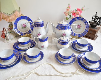May include: A vintage tea set with a blue and gold floral design. The set includes a teapot, creamer, sugar bowl, and six teacups and saucers.
