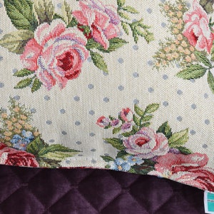 May include: A cream-colored throw pillow with a floral pattern featuring pink roses, green leaves, and blue accents. The pillow has a white polka dot background and a "Made in Italy" label.