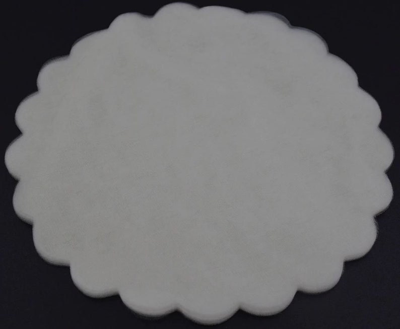 May include: A white, scalloped, round, tissue paper doily.