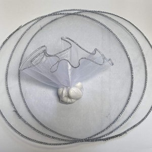 May include: White tulle favor bag with silver trim, folded into a circle shape. The bag is filled with white candy.