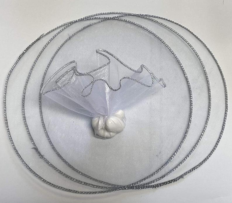 May include: White tulle favor bag with silver trim, folded into a circle shape. The bag is filled with white candy.