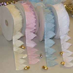 May include: Four spools of ribbon with a leaf design. The ribbons are in ivory, pink, light blue, and white.