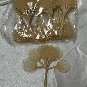 May include: A pack of 24 beige tulle flower circles with gold wire edges. The circles are attached to thin, white stems.