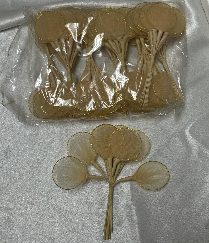 May include: A pack of 24 beige tulle flower circles with gold wire edges. The circles are attached to thin, white stems.