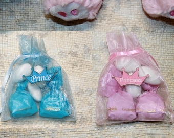 May include: Two small bags filled with white candy and tied with ribbon. One bag is blue with a wooden tag that says "Prince" and a crown. The other bag is pink with a wooden tag that says "Princess" and a crown.