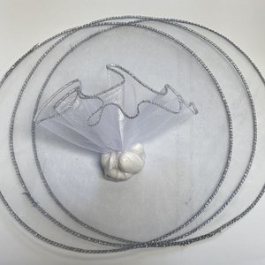 May include: White tulle favor bag with a silver trim, tied with a silver ribbon. The bag is filled with white candy.