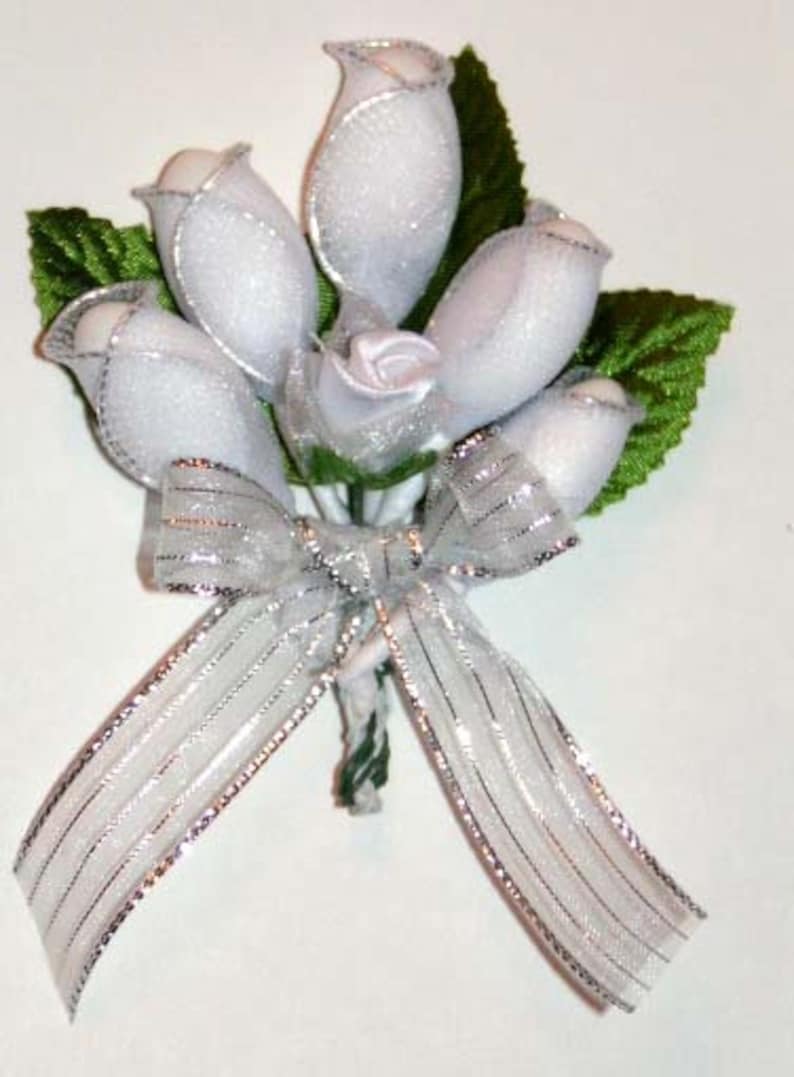 May include: A bouquet of white silk roses tied with a silver ribbon. The roses are arranged in a cluster and tied together with a silver ribbon. The bouquet is perfect for a wedding or other special occasion.