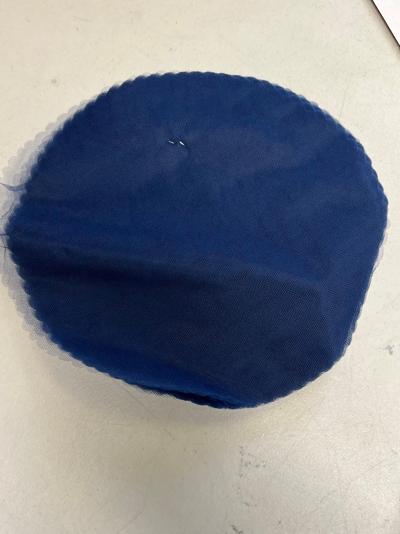 May include: A round, navy blue tulle fabric circle.