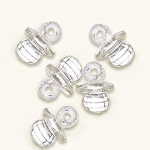 May include: Five clear plastic baby pacifier shaped charms. The charms are silver in color and have a raised design.
