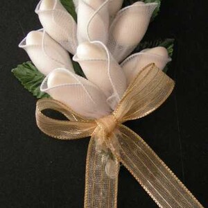 May include: A bouquet of white fabric roses tied with a gold ribbon. The roses are made of sheer fabric and are arranged in a cluster.