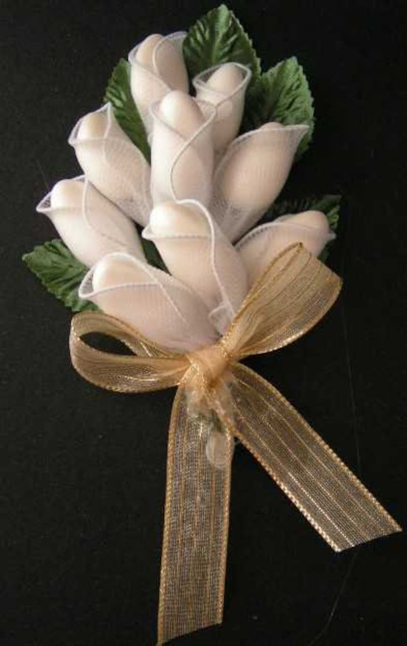 May include: A bouquet of white fabric roses tied with a gold ribbon. The roses are made of sheer fabric and are arranged in a cluster.