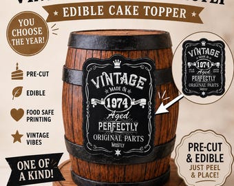 May include: An edible cake topper featuring a black label with white text that reads VINTAGE MADE IN 1974 Aged PERFECTLY ORIGINAL PARTS MOSTLY. The design includes a crown icon and decorative borders, presented on a wooden barrel surface.