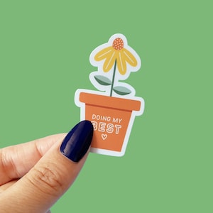 Könnte beinhalten: Ein Aufkleber mit einer Topfpflanze mit einer gelben Blume und dem Text "Doing my best" mit einem kleinen Herzsymbol.