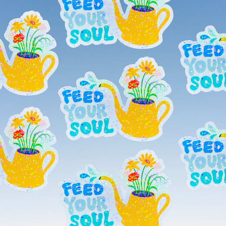 May include: Six colorful stickers with a yellow watering can filled with flowers and the text "Feed Your Soul" in blue and white lettering. The stickers have a glittery finish.