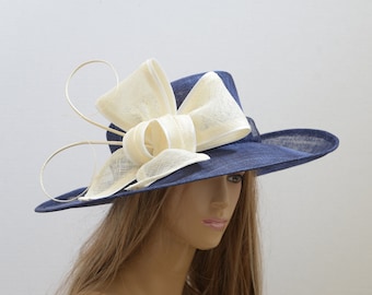 May include: A wide-brimmed navy blue hat with a large ivory bow and curled accents.