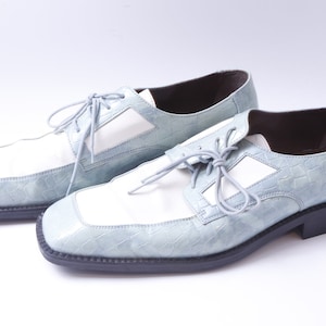May include: A pair of light blue and white leather dress shoes with lace-up closures. The shoes have a crocodile-embossed pattern.