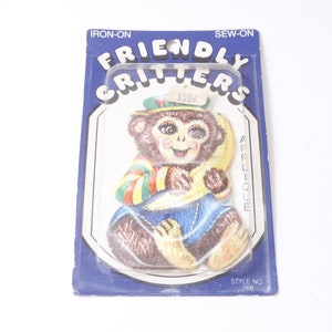 May include: An iron-on or sew-on applique featuring a cartoon monkey wearing a green hat and holding a yellow banana. The applique is labelled "Friendly Critters" and "Applique" and has the style number 269.