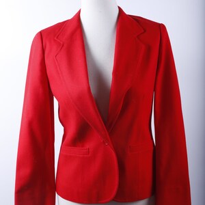 May include: A red blazer with long sleeves and a single button closure. The blazer has a classic, tailored fit.
