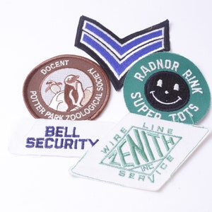 May include: Five embroidered patches, including a brown patch with a penguin and the text "Potter Park Zoological Society Docent", a green patch with a smiley face and the text "Radnor Rink Super Tots", a blue and white patch with two stripes, a white patch with the text "Bell Security", and a white patch with the text "Zenith Wire Line Inc. Service".