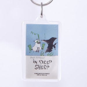 May include: A clear plastic keychain with a cartoon illustration of a sheep wearing scuba gear and a shark. The text on the keychain reads "David Silverman" and "In Deep Sheep".