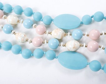 May include: A multi-strand necklace with light blue, pink, and white beads. The necklace features large, oval-shaped beads in light blue and smaller round beads in pink and white.