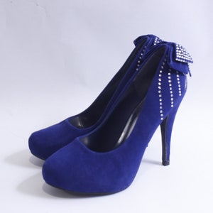 May include: A pair of blue suede high heels with a rhinestone bow detail.