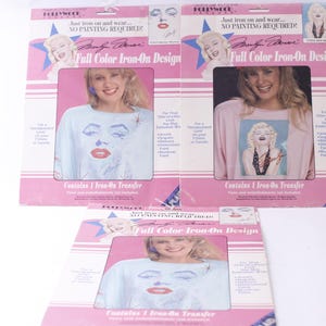 May include: Three packages of iron-on transfer designs featuring a portrait of Marilyn Monroe. Each package includes one iron-on transfer and instructions. The packages are pink and white with the text "Full Color Iron-On Design" and "Just iron on and wear... NO PAINTING REQUIRED!"
