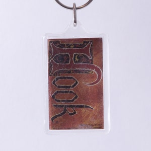 May include: A clear plastic keychain with a red and gold image of the word "Rook" in a decorative font.