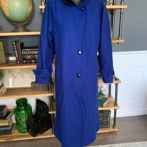 May include: A long, royal blue wool coat with a black velvet collar and three black buttons down the front.
