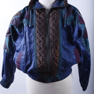 May include: A blue, brown, teal, and purple quilted jacket with a zipper closure.