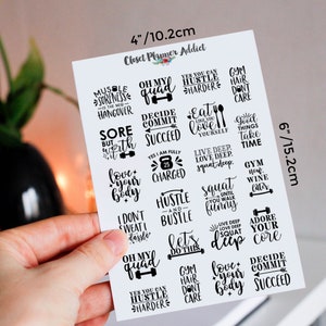 Op de afbeelding: Een vel met 16 witte stickers met zwarte tekst en afbeeldingen. De stickers bevatten motiverende citaten en zinnen die te maken hebben met fitness, lichaamsbeweging en een gezonde levensstijl. Het vel meet 15,2 cm bij 10,2 cm.