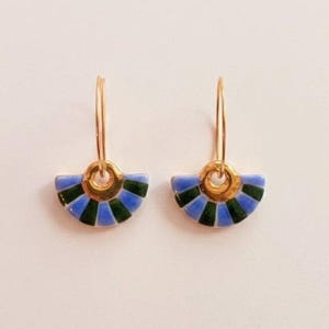 Peut inclure: Une paire de boucles d'oreilles créoles en or avec un pendentif en forme d'éventail. Le pendentif est orné de rayures alternées en émail bleu et vert foncé, formant un motif semi-circulaire segmenté suspendu à un anneau en or.