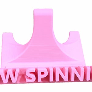 K&ouml;nnte beinhalten: Ein rosa 3D-gedruckter Telefonst&auml;nder mit dem Schriftzug "NOW SPINNING" auf der Vorderseite.