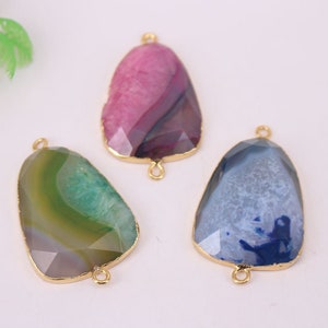 Puede incluir: Tres colgantes de piedra de ágata con bucles de metal dorado. Los colgantes son en tonos de rosa, verde y azul.