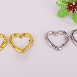 May include: Two gold heart-shaped clasps and two silver heart-shaped clasps. The clasps are metal and have a spring-loaded mechanism.