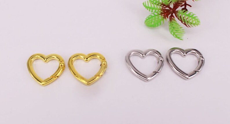 May include: Two gold heart-shaped clasps and two silver heart-shaped clasps. The clasps are metal and have a spring-loaded mechanism.