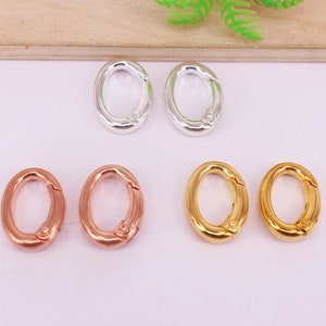 May include: An assortment of oval-shaped clasps in silver, rose gold, and gold tones. The clasps are shown open and closed, showcasing their functionality. These jewelry findings are ideal for various crafting projects.