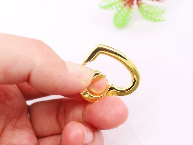 May include: A gold-colored heart-shaped metal clasp with a spring-loaded opening.