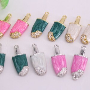 Puede incluir: Surtido de dijes de paleta de helado con detalles dorados y plateados. Los dijes est&aacute;n hechos de metal y tienen un acabado de esmalte colorido. Algunos dijes tienen diamantes de imitaci&oacute;n transparentes.