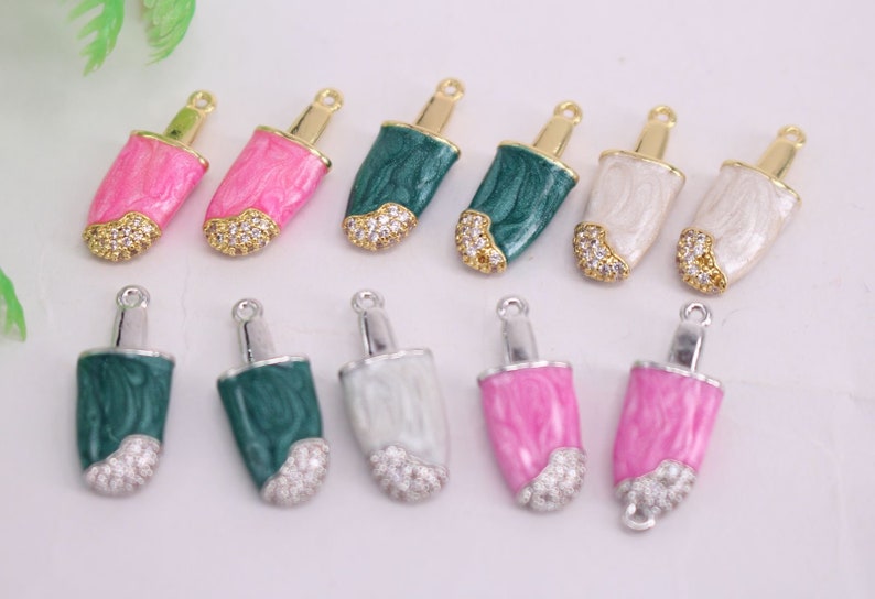 Puede incluir: Surtido de dijes de paleta de helado con detalles dorados y plateados. Los dijes est&aacute;n hechos de metal y tienen un acabado de esmalte colorido. Algunos dijes tienen diamantes de imitaci&oacute;n transparentes.
