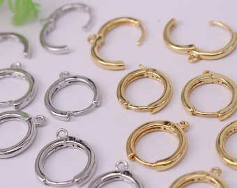 Op de afbeelding: Een verzameling gouden en zilveren oorbel-bevestigingen in de vorm van cirkels. De bevestigingen hebben een scharnier sluiting en een springring om bedels of andere sieraden onderdelen aan te bevestigen.