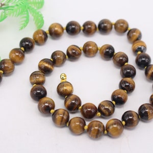 Puede incluir: Un collar de cuentas de ojo de tigre marrón y dorado con cierres dorados.