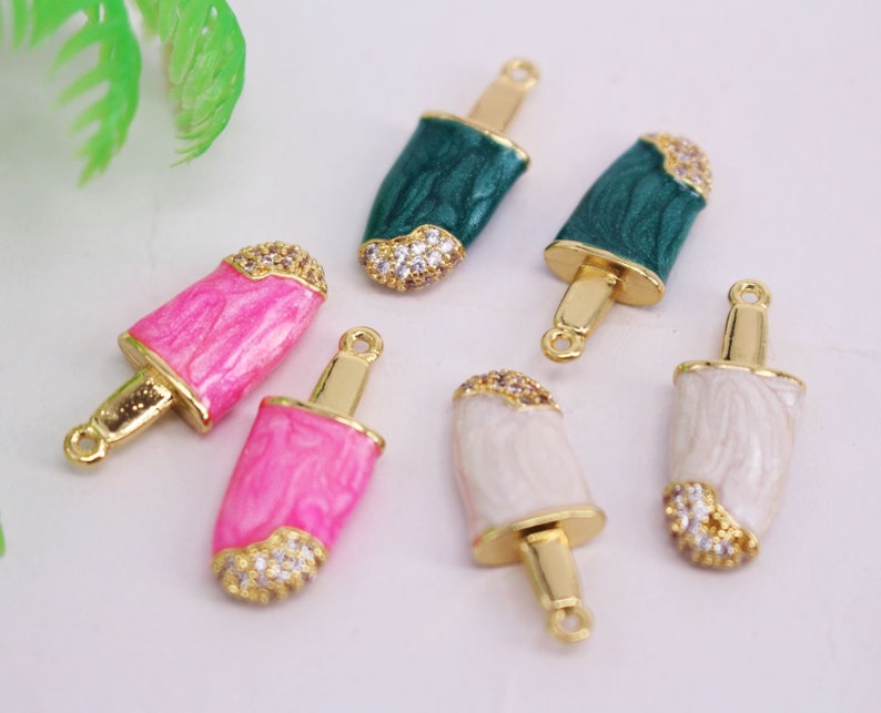 Puede incluir: Seis abalorios de paleta de helado de tono dorado con esmalte blanco, rosa y verde y detalles de diamantes de imitaci&oacute;n transparentes. Los abalorios tienen un bucle en la parte superior para sujetarlos a joyas.