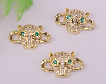 May include: Three gold-tone metal charms shaped like a panther's head with clear and green rhinestones. The charms have a loop on each side for attaching to jewelry.
