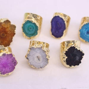 May include: Seven gold rings with different colored agate stones. The stones are all in a flower shape and have a gold setting.