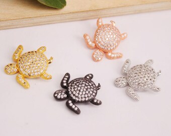 May include: Four turtle charms with clear crystal accents. The charms are in gold, silver, rose gold, and black.
