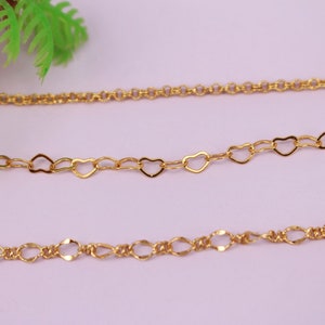 Op de afbeelding: Drie gouden kettingen met verschillende schakelstijlen. De bovenste ketting heeft een eenvoudige ronde schakel, de middelste ketting heeft hartvormige schakels en de onderste ketting heeft een meer ingewikkelde ovale schakel.